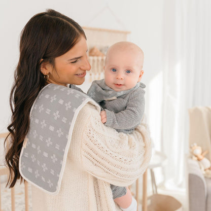 Parent holding baby with Crane Baby woodland burp cloth