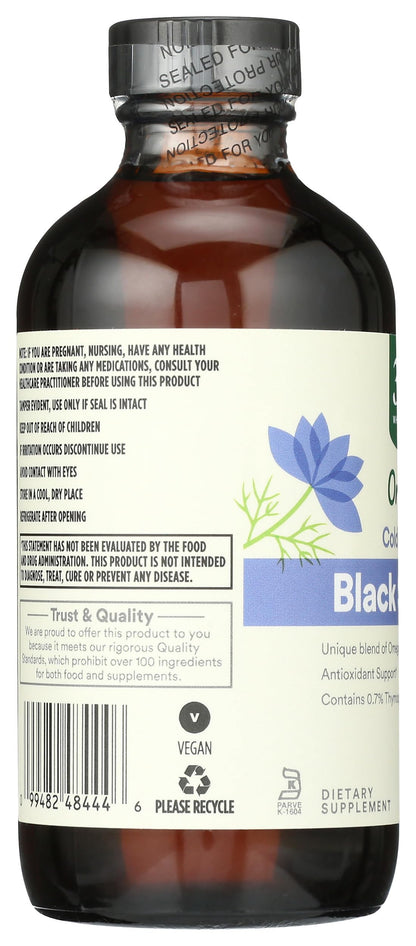 Pouring organic unrefined black cumin seed oil showing its rich natural golden texture