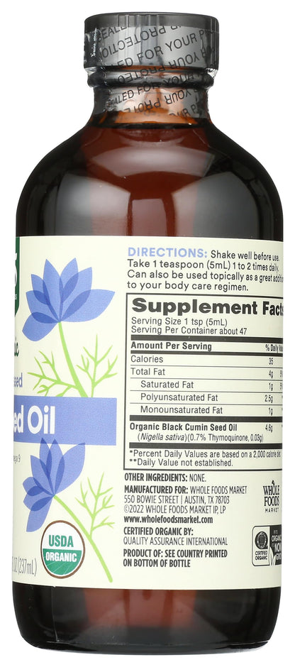 Whole Foods Market black seed oil bottle placed next to natural herbal ingredients for wellness