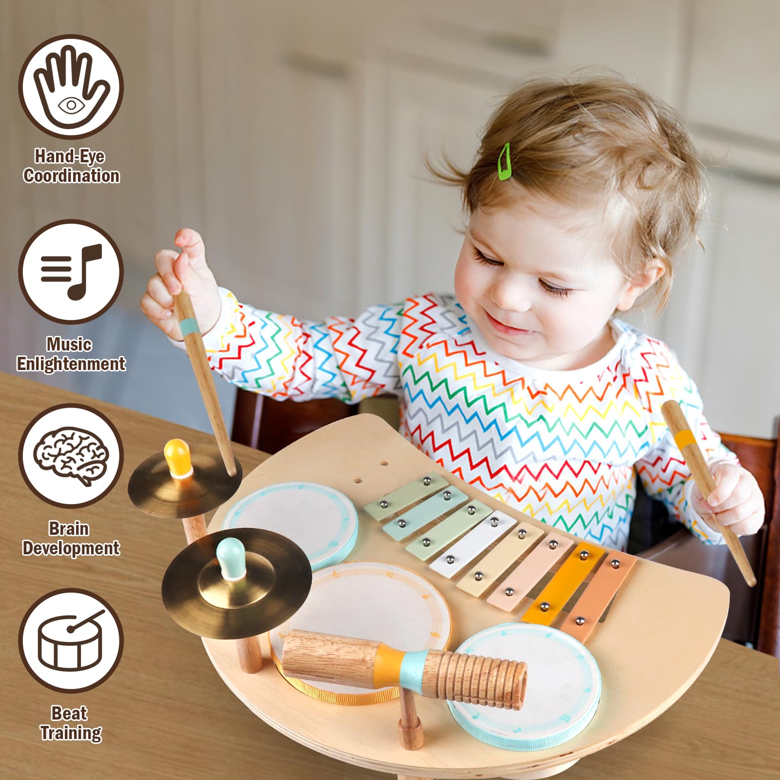 Toddler hands holding the two wooden drumsticks striking the mini cymbals on the activity table.