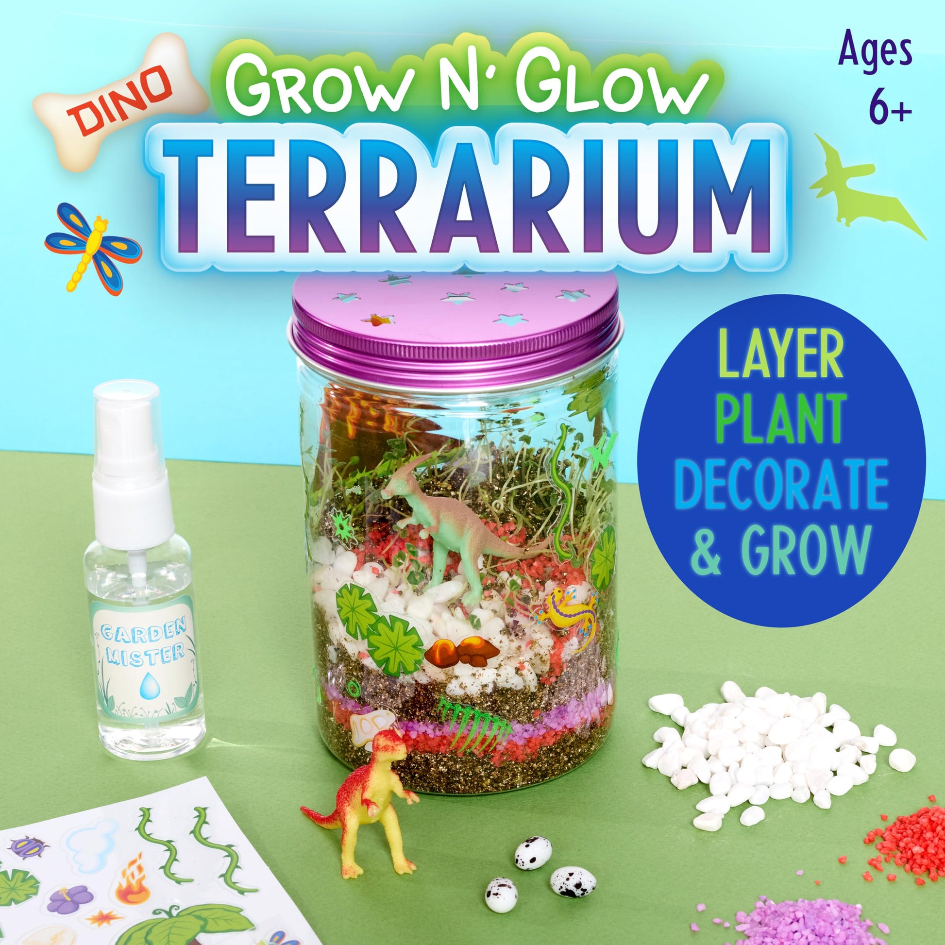 Assembled dinosaur terrarium jar filled with sprouted green plants, colored sand layers, and toy figurines.