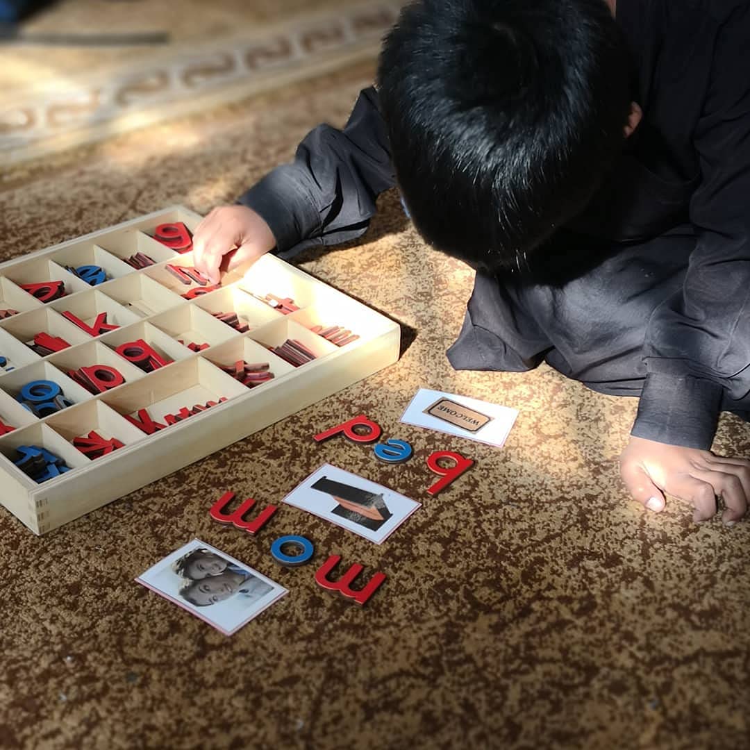 Top down lifestyle perspective of a child using the color coded blue vowels and red consonants for literacy training
