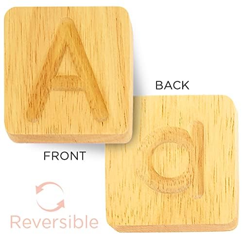 Toddler hand using the wooden dummy pencil stylus to trace engraved alphabet groove tiles.