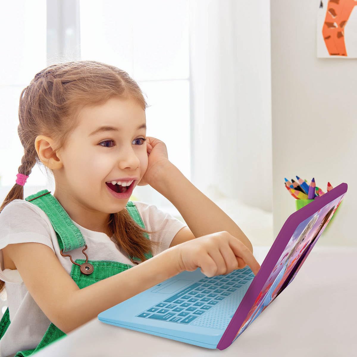 A young girl interacting with the attached functional mouse on the blue and purple Frozen educational laptop.