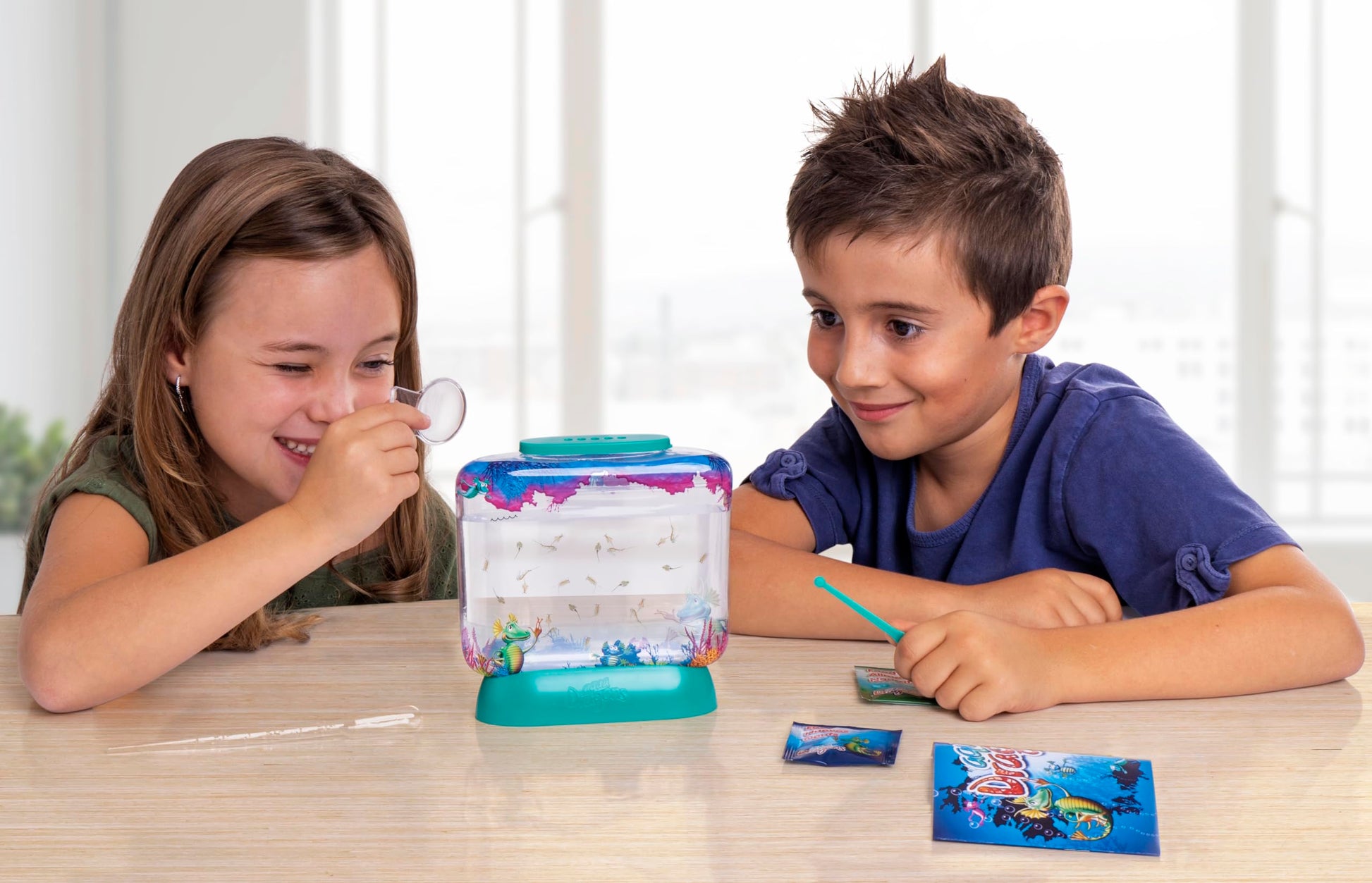 Children observing the live brine shrimp ecosystem using the integrated magnifying lens