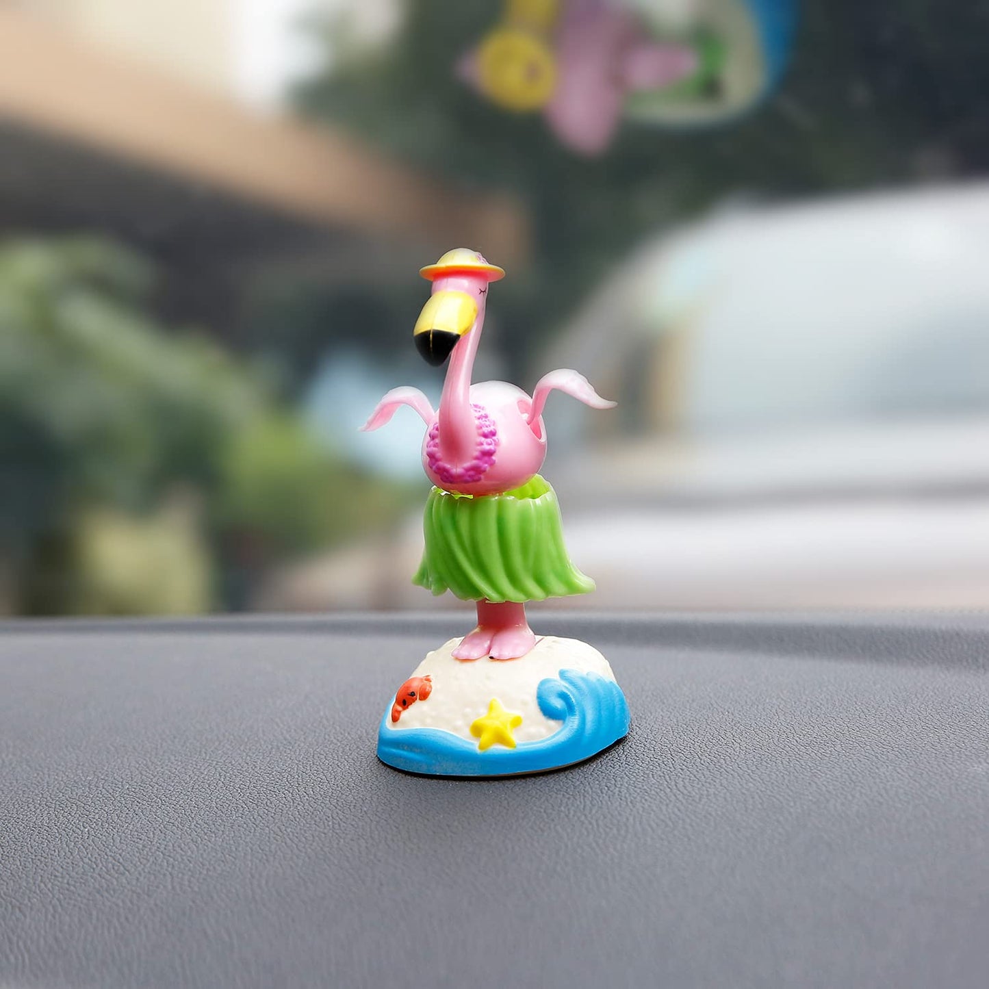 YGMONER solar hula flamingo doll resting on a sunny car dashboard reflecting tropical holiday vibes