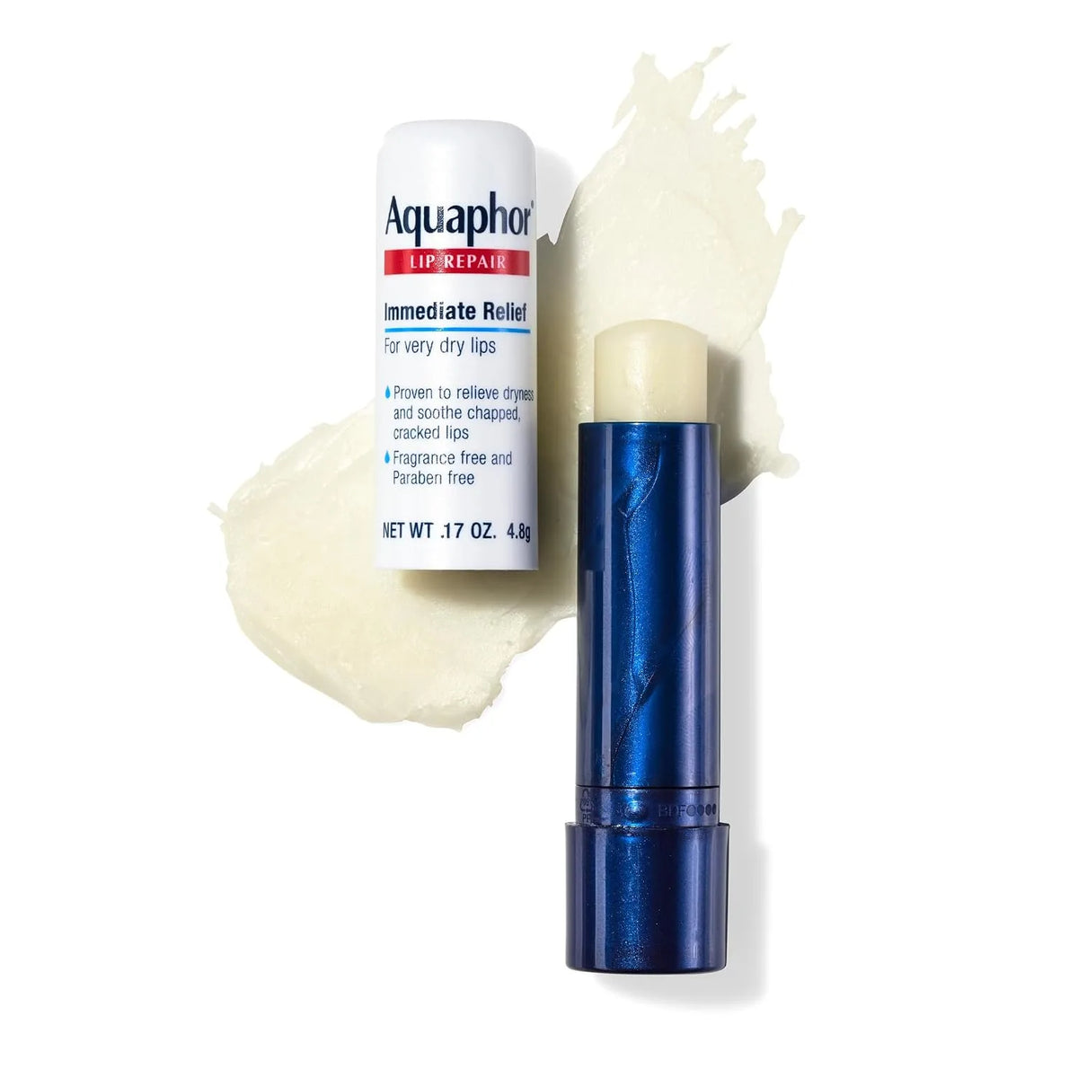 Aquaphor Lip Repair Immediate Relief lip balm shown with its white cap and a dark blue tube, set against a white background with a beige cream smear behind it.