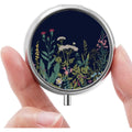 HCYPCV mini pill box front view showing the vintage black flowers decorative pattern on the metal shell.