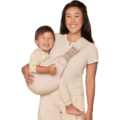 Ergobaby Upsie Hip Sling Natural Beige front view being worn by a parent.