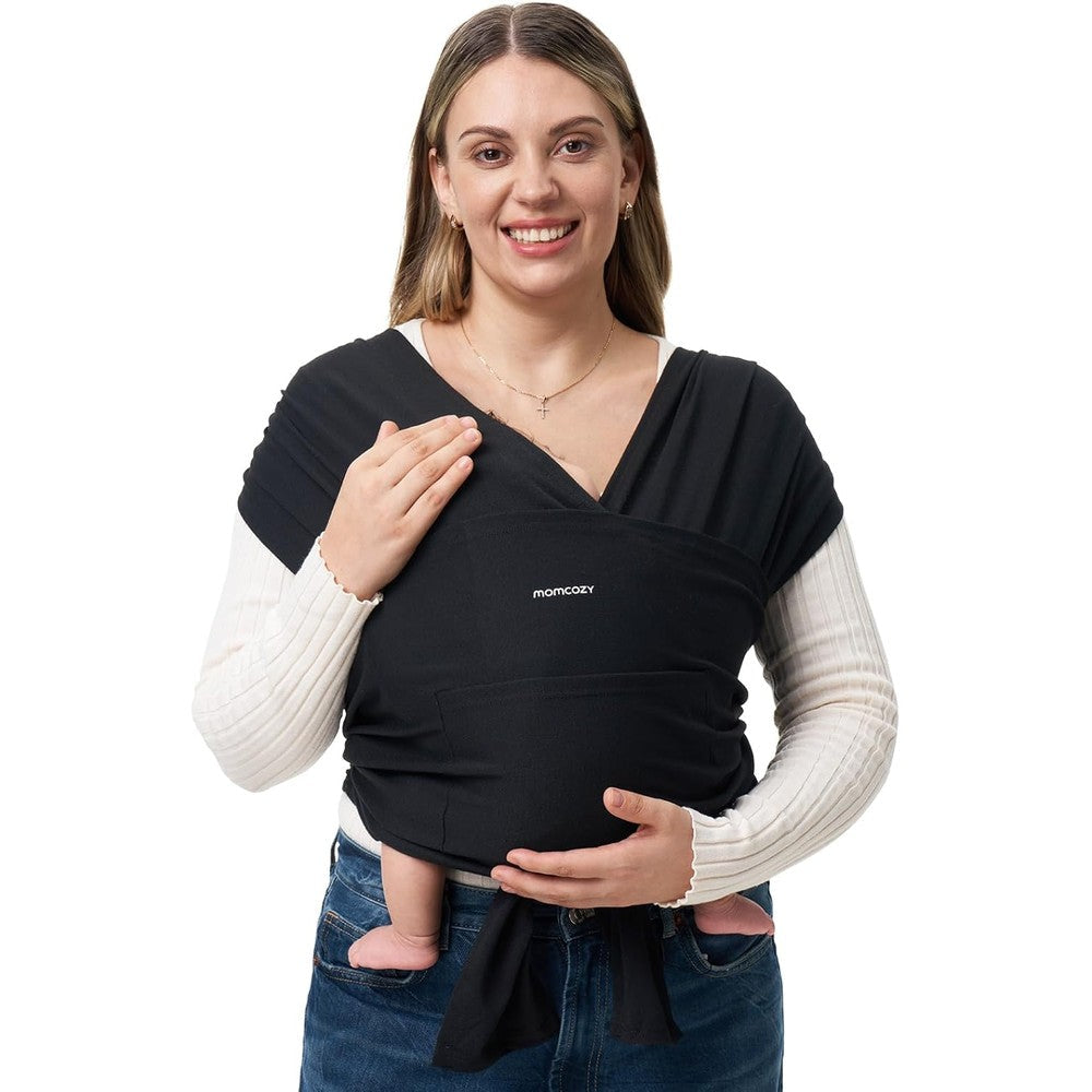 Momcozy Baby Wrap Carrier front view showing a mother wearing the black adjustable fabric sling.