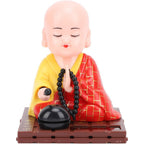 Tyenaza Little Monk Figurine front view showing red robe and solar panel on car dashboard.