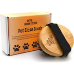 The Buddy System Pet Close Brush front view showcasing the ergonomic oval bamboo design and elastic hand strap.